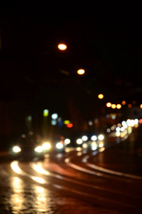 道路上交通的模糊夜景。 用发光前照灯旅行的汽车的离焦图像。 波克艺术