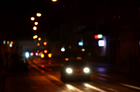 道路上交通的模糊夜景。 用发光前照灯旅行的汽车的离焦图像。 波克艺术