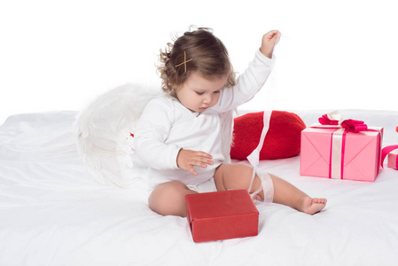 小天使坐在床上，把礼品盒隔在白色上