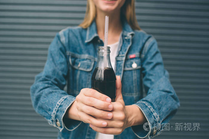 饮料人和生活方式概念接近快乐的女人喝可乐与稻草附近的灰墙