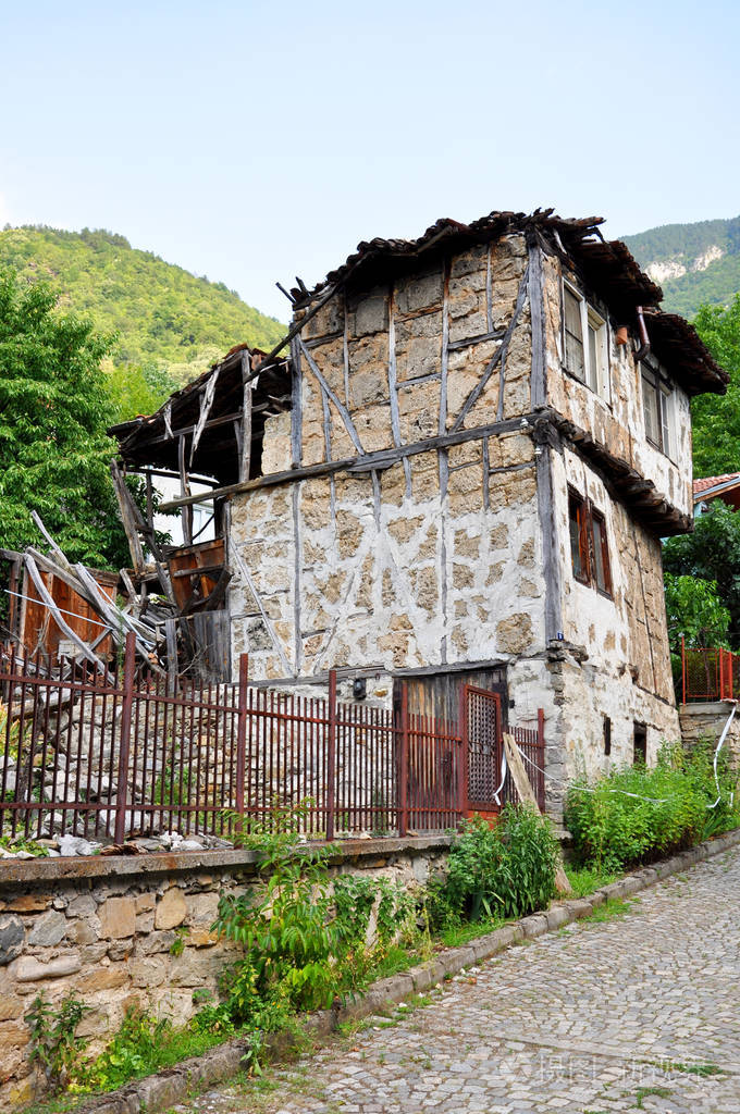 乡村街道上铺着石头路和山峦背景上的老房子