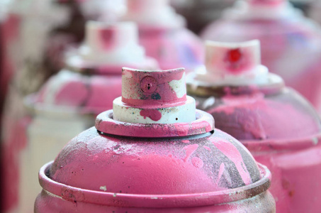 很多脏的和用过的气溶胶罐的明亮的粉红色油漆。 具有浅场深的宏观照片。 有选择地专注于喷嘴