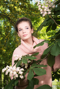 一个美丽的年轻女子在一个郁郁葱葱的花园粉红色毛衣纵向肖像