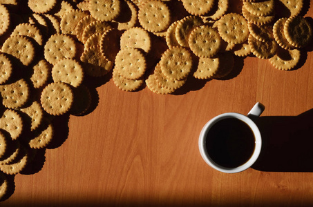 背景图片一小杯白色咖啡和经典咸味饼干在棕色木桌与共空间