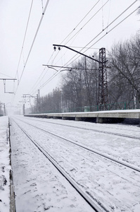浓雾下大雪的空火车站。 铁路铁轨在白雾中消失了。 冬季铁路运输的概念