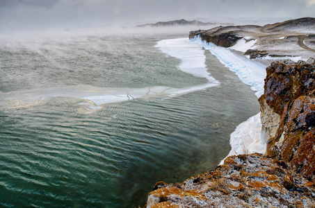 贝加尔湖和岩石在12月的寒冷。冰冻的时间。冰浮冰在水上游泳