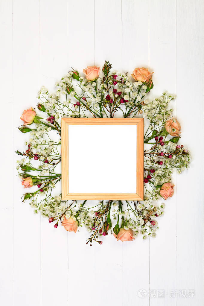美丽的花朵和木制的相框在白色的木桌上.平躺式