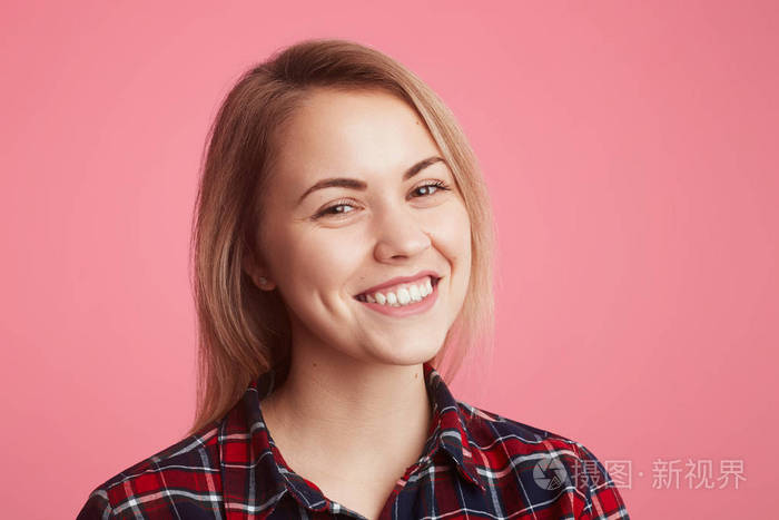 欢快美丽的女性肖像有灿烂的笑容, 穿着休闲格子衬衫, 表达积极的情绪