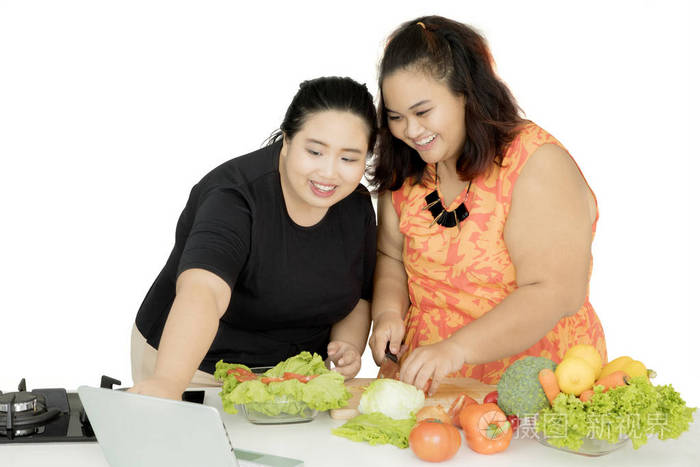 两个胖女人用笔记本电脑做饭