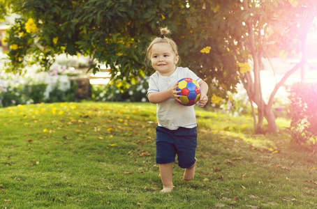 快乐可爱的宝贝男孩玩在绿色草地上的球