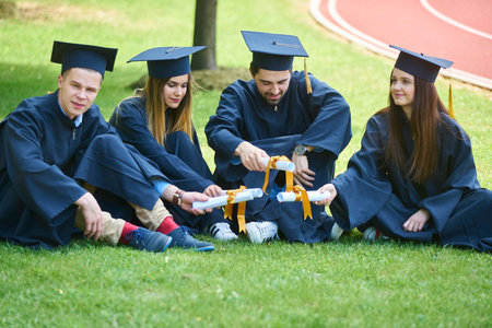 教育毕业和人的概念小组快乐的国际学生在灰泥板和学士学位礼服与文凭