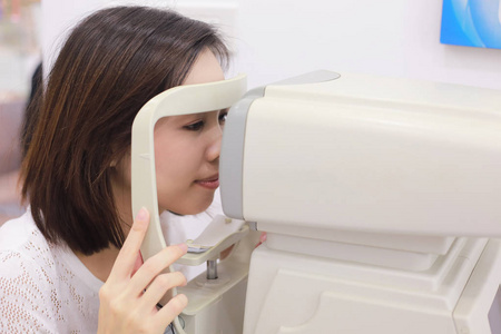 女性眼科验光师机在医疗室做眼部检查照片