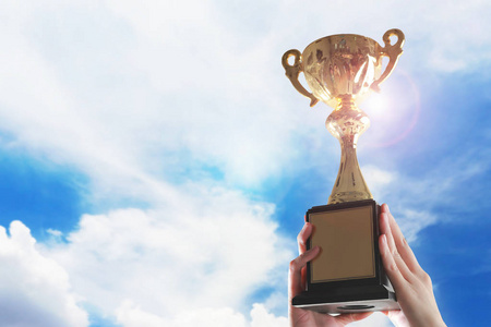 商务手捧奖杯杯在天空背景照片