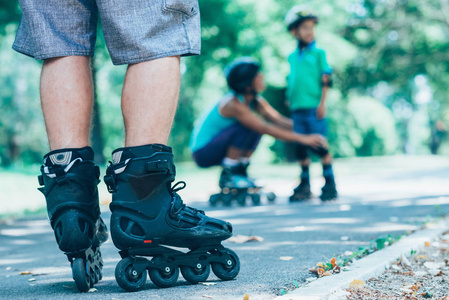 s Roller skaters in focus with mother and son in background