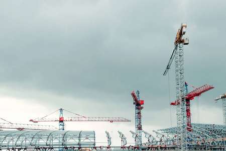 大型工业塔式起重机,未完成的高层建筑和蓝天背景. 脚手架.