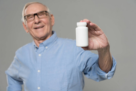 年长自信的男人拿着白色的药丸，在灰色背景下隔离