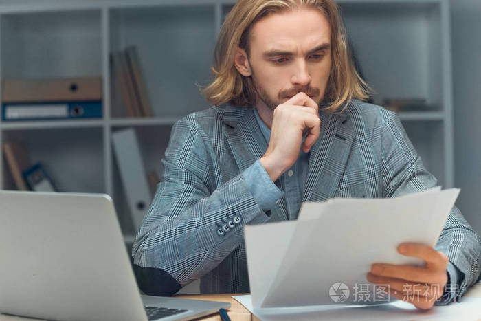 一个有思想的白种人坐在桌子上拿着纸