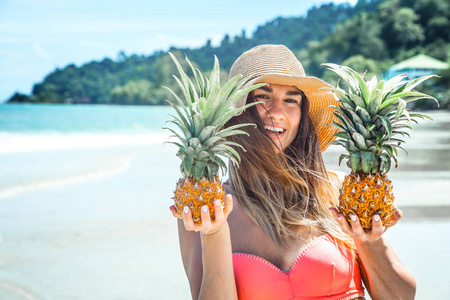 美丽的女孩与菠萝在异国情调的海滩, 一个愉快的心情