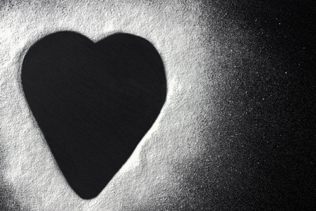 情人节概念白面粉心形黑色背景照片