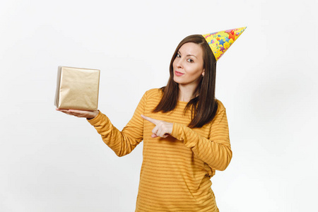 欢快的白种人年轻快乐的女人穿着黄衣服, 生日派对帽拿着礼品盒, 在白色背景上庆祝节日, 为广告而孤立。与地方为文本