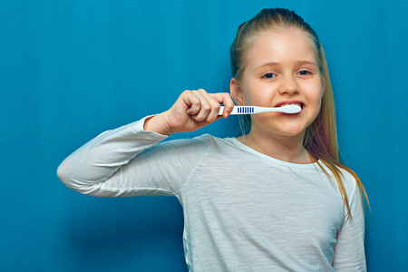 蓝墙背景的小女孩用牙刷刷牙图片