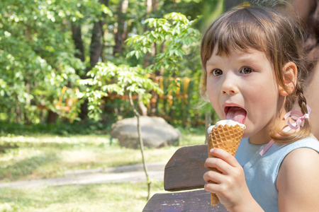 可爱的小女孩吃冰淇淋在城市公园在夏天 s