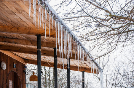 屋檐的雪挂在房子屋顶屋檐上的冰柱. 冬季解冻照片