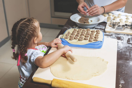 小女孩擀面团，而她的母亲则为节日做饺子造型