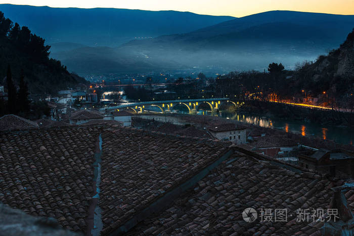 傍晚的贝拉特，小镇是阿尔巴尼亚的南部，它的山丘上覆盖着薄雾，照亮了奥苏姆河上的戈里察桥和瓦屋顶的旧建筑。