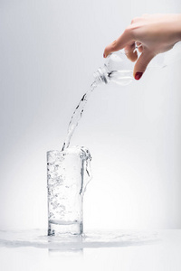 女人用塑料瓶把新鲜水倒进玻璃里