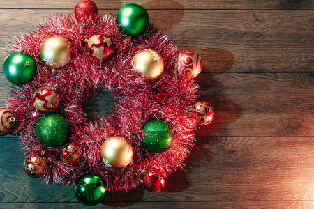 木制桌子背景上红色花环和圣诞玩具的圣诞花环。 圣诞快乐，节日快乐。 从上面看。