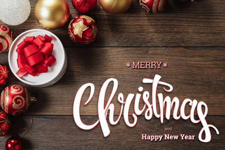 圣诞快乐的铭文和新年快乐的装饰品和礼物在一张木制的棕色桌子上。 圣诞卡假日背景。 混合媒体。