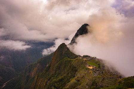 马丘比丘被从开放云出来的第一束阳光照亮。印加的城市是在秘鲁访问量最大的旅游目的地。雾 云和雾覆盖的山谷