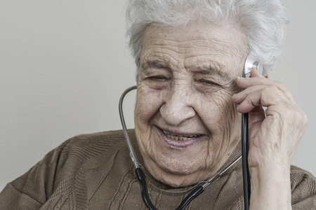 一位老年妇女用听诊器听着她的头