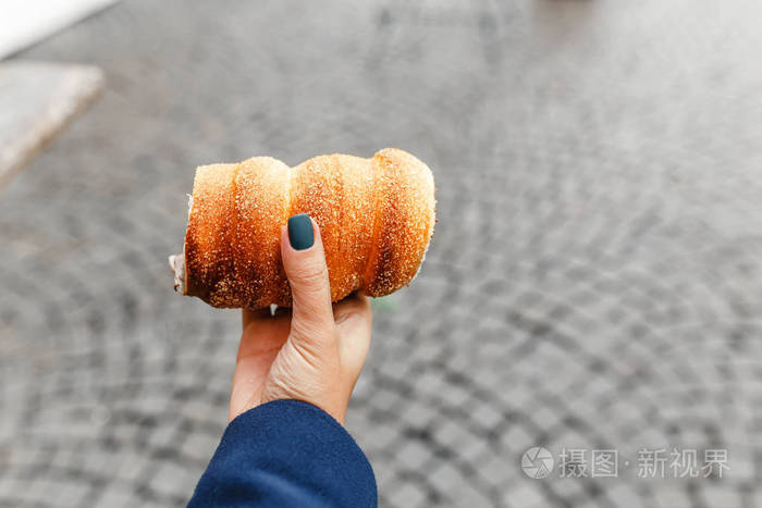 妇女手捧trdlo或trdelnik它是一个全国性的街头食品的背景下的城市
