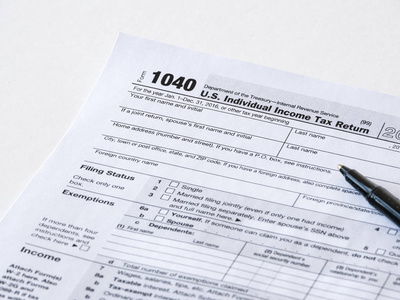 用黑色圆珠笔关闭美国1040个人所得税申报表的照片，适合纳税日或纳税季节背景或壁纸图像。