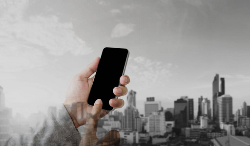 商人手用手机智能手机双曝光现代城市背景空白黑屏