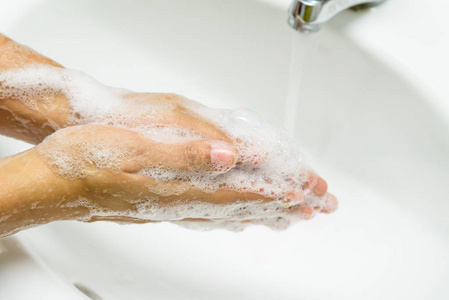 特写女人用肥皂在水龙头下用清水洗手