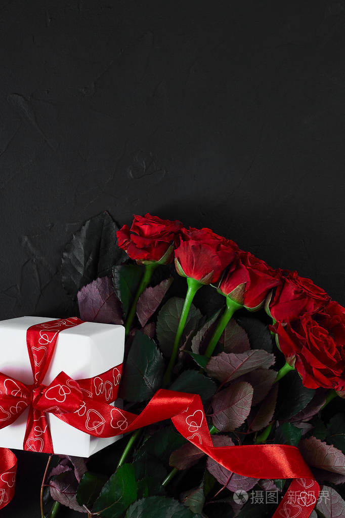 顶部查看新鲜红玫瑰花和礼品盒在黑色甲板上与 e