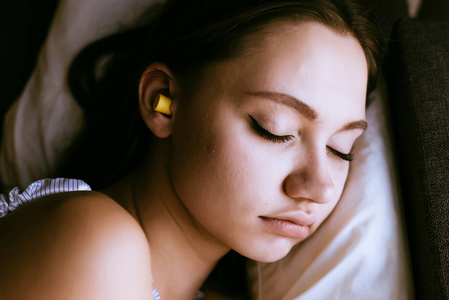 可爱的年轻女孩睡觉, 在耳朵黄色耳塞反对噪声