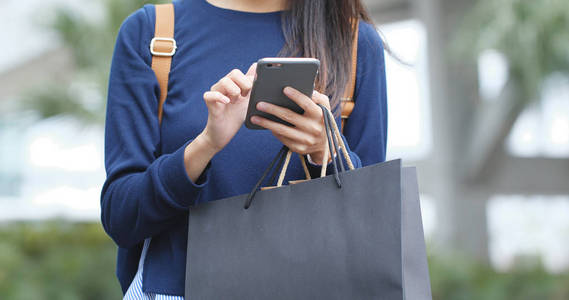 女人用手机拿着购物袋