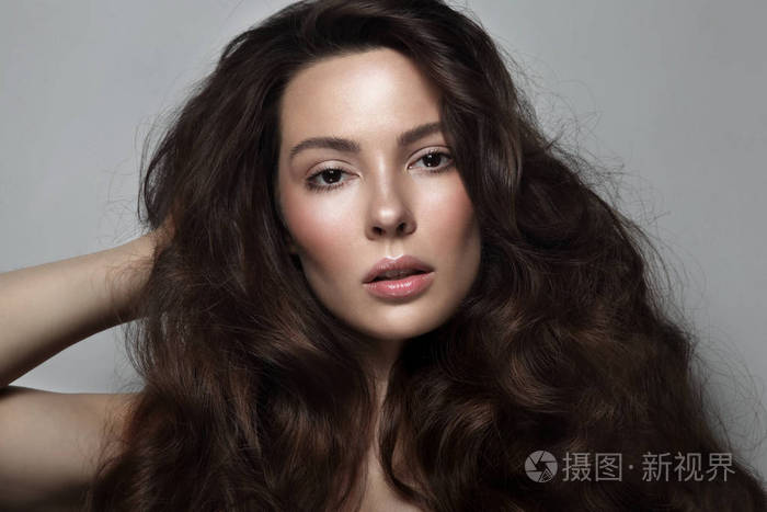 年轻漂亮的女人留着长长的卷发梳洗打扮