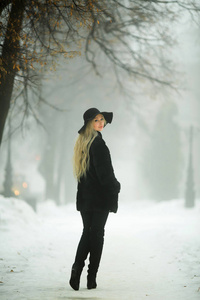 冬天的天气，穿着毛皮外套和帽子在公园里散步的漂亮年轻女孩