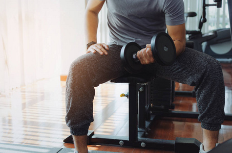 肌肉发达的亚洲年轻帅哥用哑铃在肱二头肌做运动,以保持良好的身体在