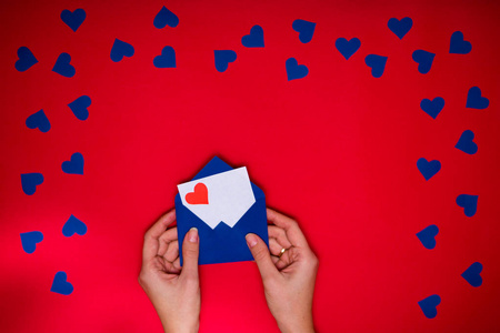 s hands hold envelope with love letter above red background with