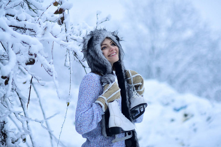 愉快的女孩微笑与图冰鞋在树在雪