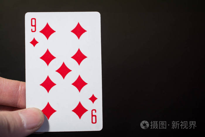 人手拿着扑克牌九的钻石在黑色背景下被孤立copyspace抽象