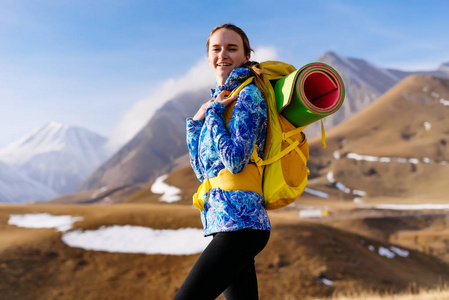 快乐的旅游女孩与大背包在山的背景