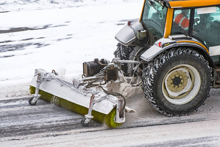 冬季暴风雪期间在路上工作的大型雪耕拖拉机机