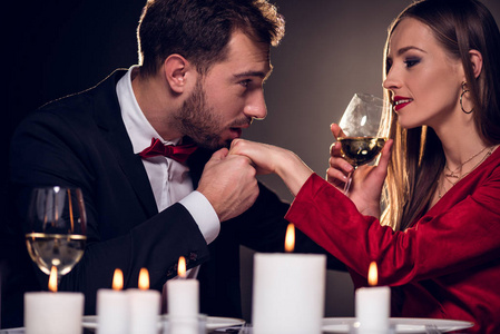 女人喝酒，而男人在餐馆浪漫约会时亲吻她的手